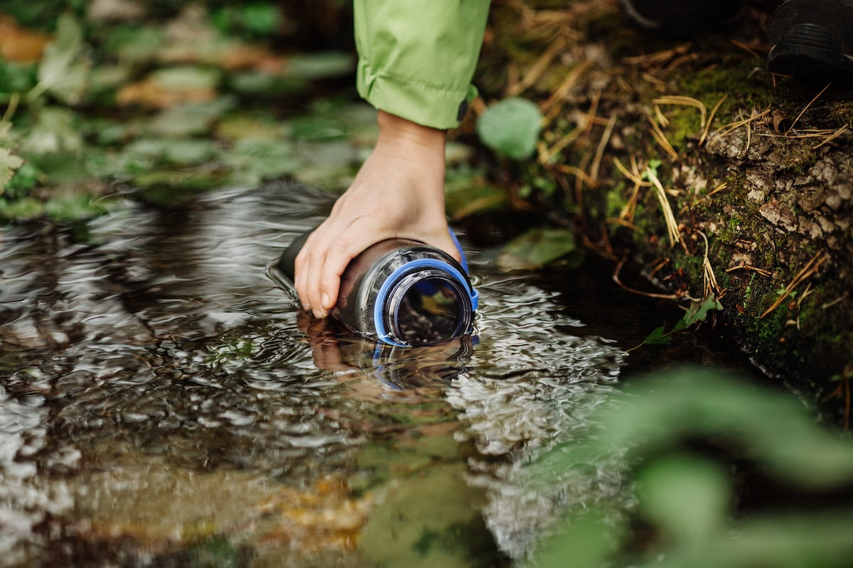 Filling water bottle in stream