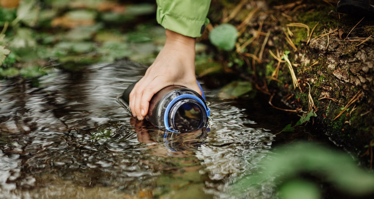 Filling water bottle in stream